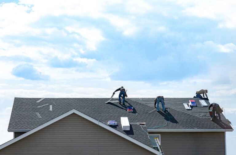 A residential roof showing asphalt shingles, standing-seam metal panels, and slate samples beside a snowy home.